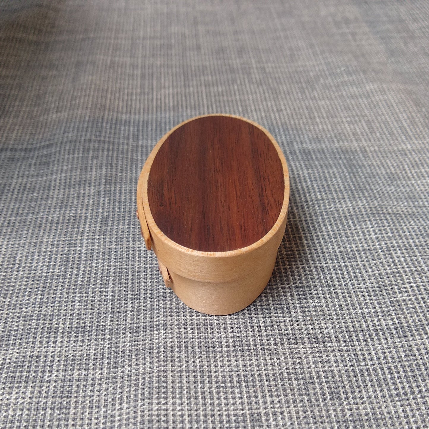 Handmade wooden Shaker oval #00 box with a walnut lid on a gray tablecloth