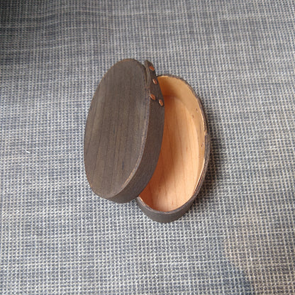 Handmade wooden Shaker oval #00 box with a black/grey outside and a natural maple inside, on a gray tablecloth