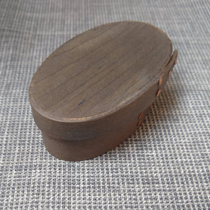 Handmade wooden Shaker oval #00 box with a black/grey outside and a natural maple inside, on a gray tablecloth