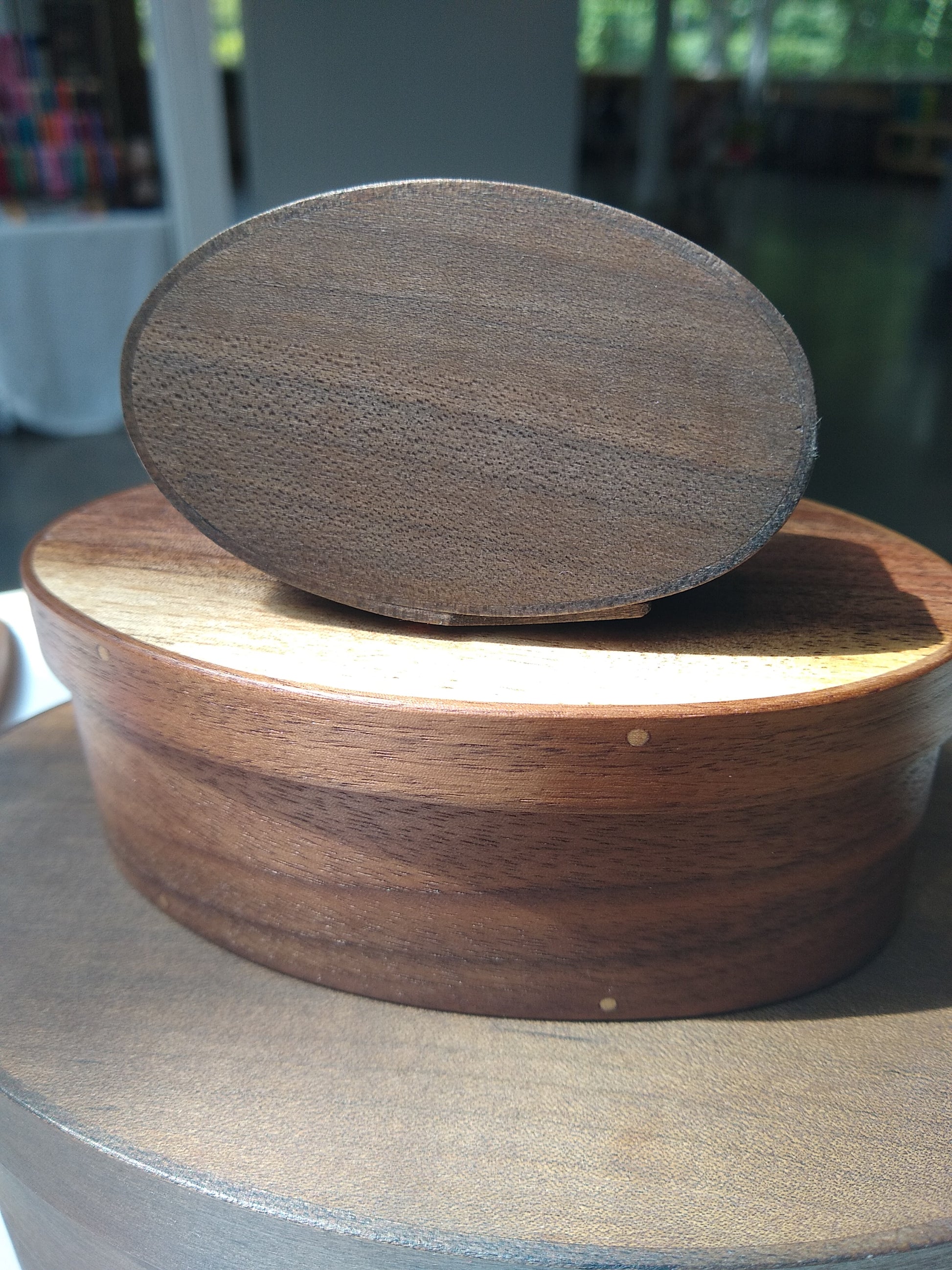 Handmade wooden Shaker oval #00 box with a black/grey outside and a natural maple inside, on a gray tablecloth